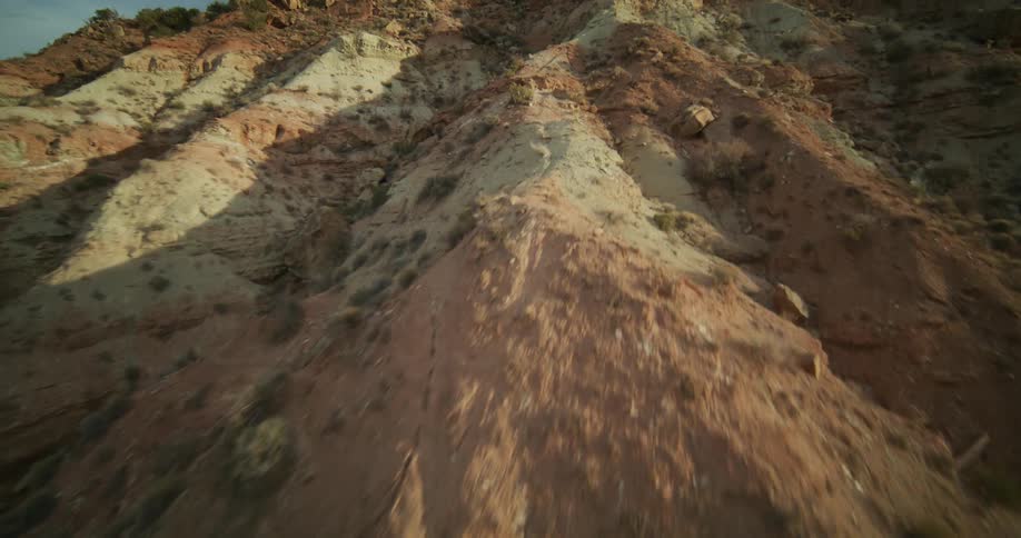 An adventurous FPV drone flight ascending the sun-kissed, rugged spine of a desert mountain