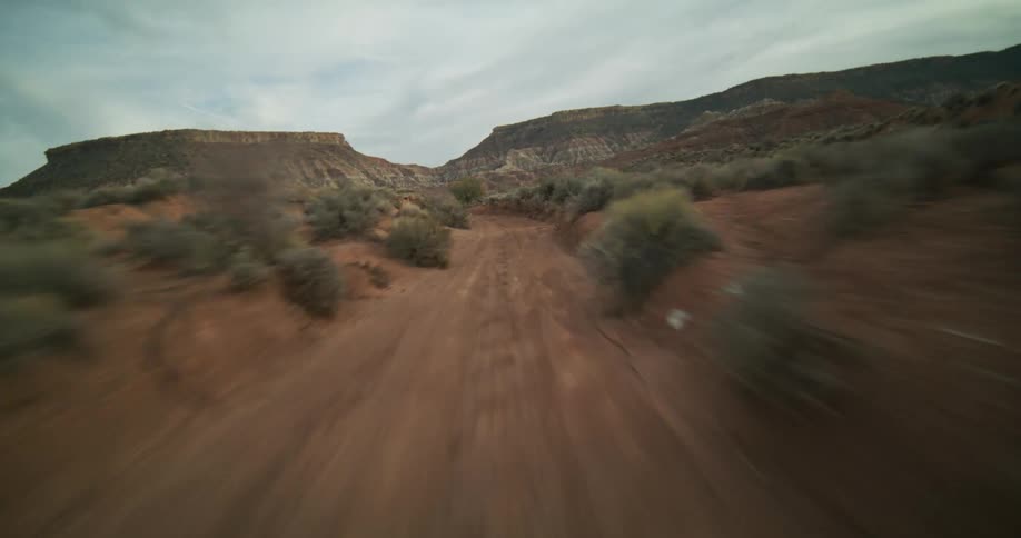 A fast-paced, first-person point-of-view drive on a rugged dirt road through a stunning red rock desert canyon
