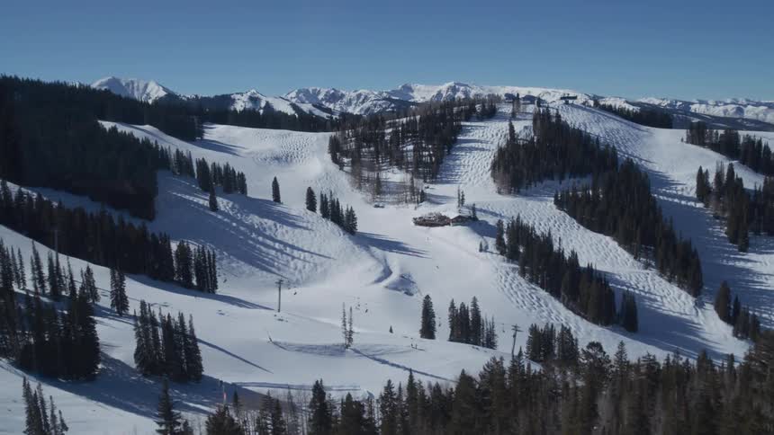 A stunning panoramic view of a vast ski resort covered in fresh snow with ski lifts operating on a bright, sunny day