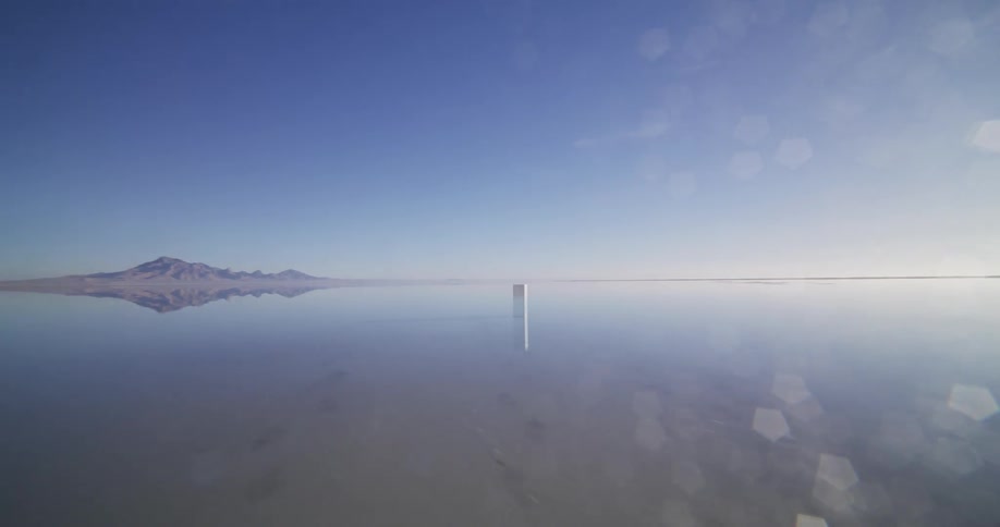 A surreal pan across a vast salt flat reveals a mysterious white monolith standing in mirror-like shallow water