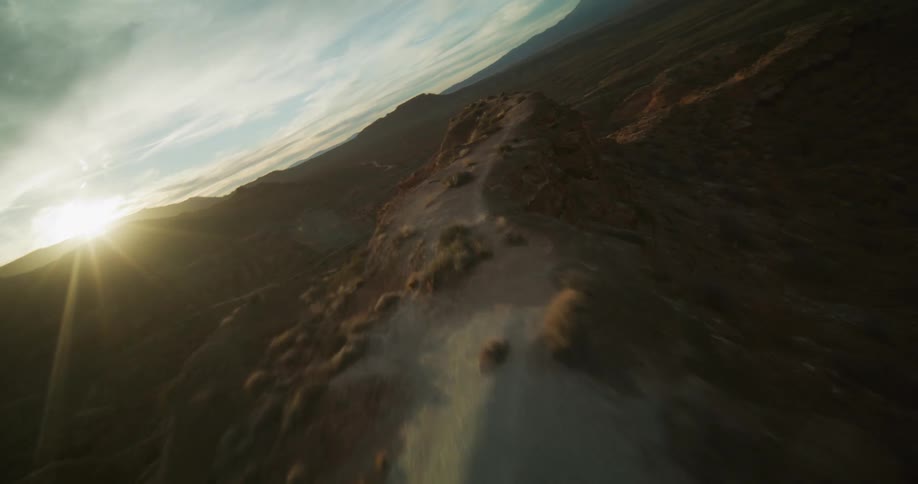 A thrilling aerial flight reveals a vast desert canyon landscape during a beautiful golden hour sunset