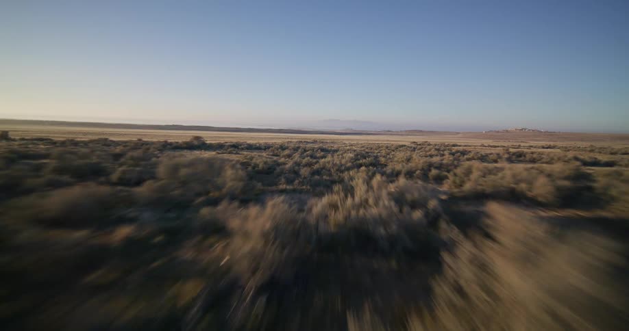 An exhilarating aerial view flying low and fast over the expansive desert plains at dawn