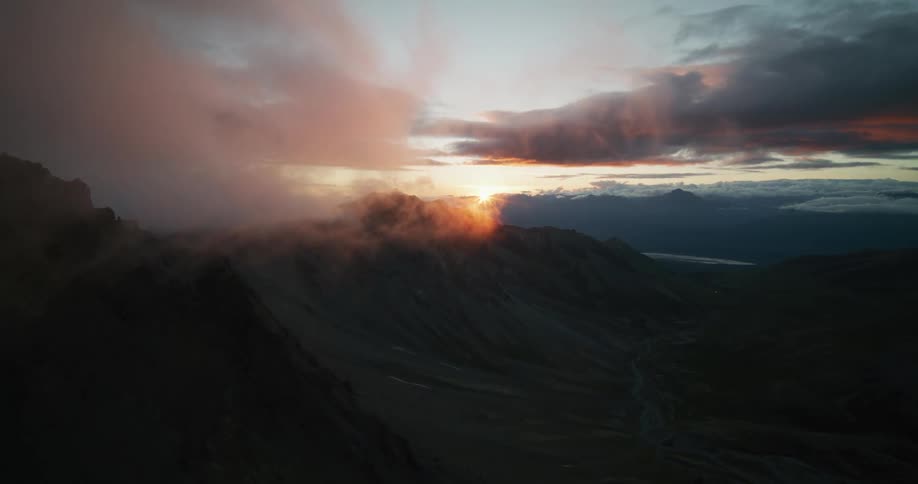 An epic aerial flight towards a spectacular sunset over a vast, misty mountain range