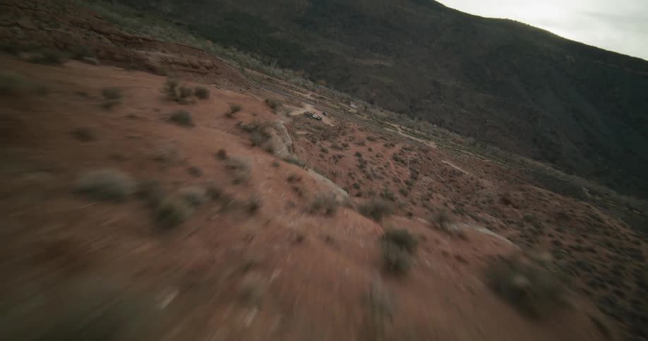 An exhilarating first-person view drone flight soaring at high speed along the spine of a red rock formation in a vast desert landscape