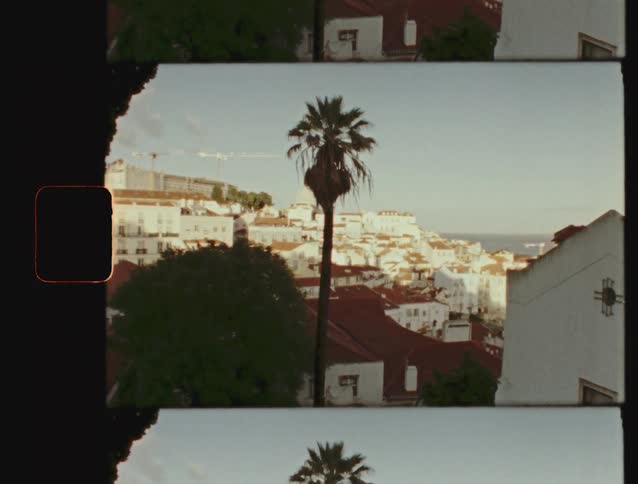 A nostalgic Super 8 film scan shows a sunny day over the historic rooftops and palm trees of Lisbon, Portugal