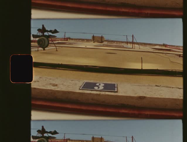 Vintage 8mm film scan looking up at the facade of a building with the number three on a blue plaque