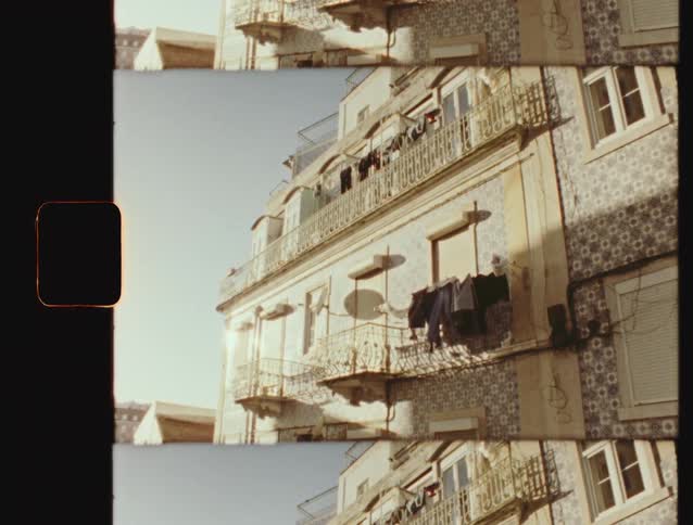 Laundry hangs to dry on the sunny balcony of a traditional tiled building in Lisbon in a vintage 8mm split-screen style