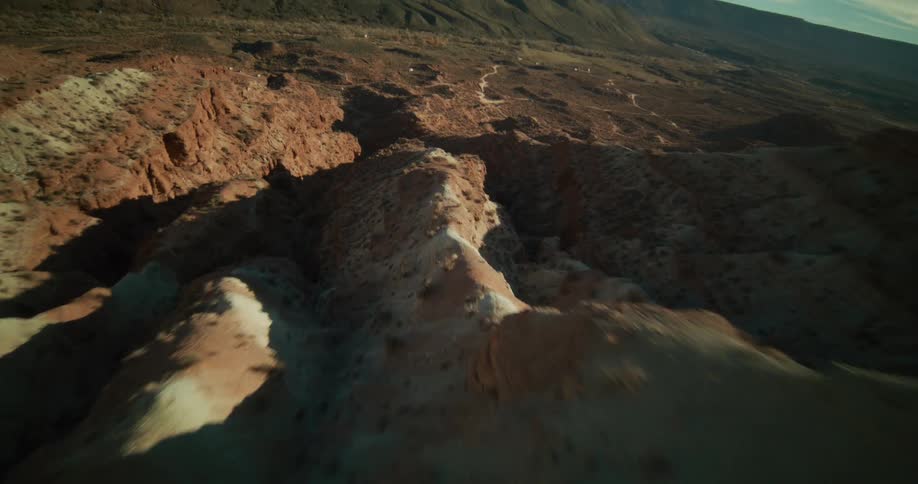 An exhilarating first-person view drone flight soars over the rugged red rock ridges and deep canyons of a sunny desert landscape
