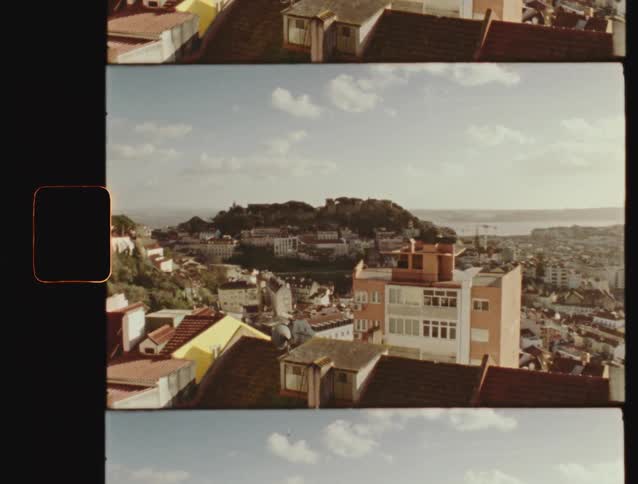 A vintage Super 8mm film scan captures a static, sun-drenched view of the historic cityscape of Lisbon, Portugal