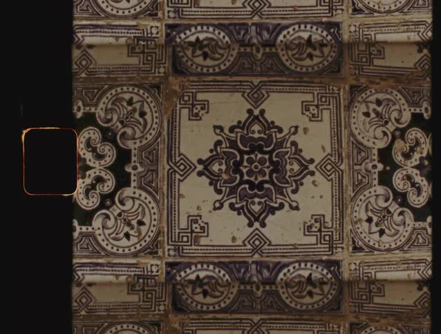 A close-up static shot of vintage, ornate Portuguese Azulejo ceramic tiles with a classic Super 8 film effect