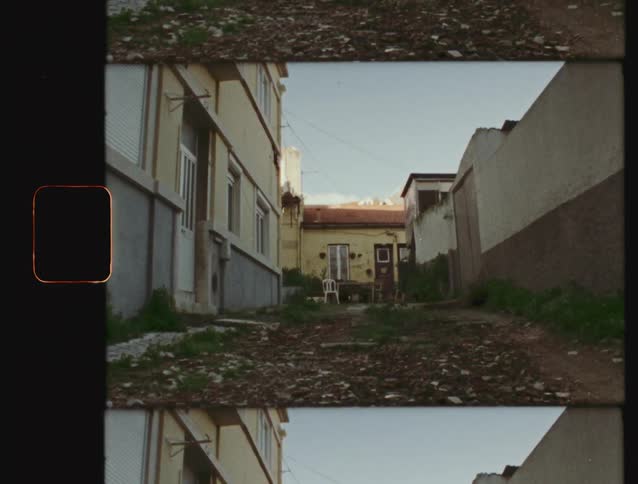 Vintage film shot of a deserted, overgrown urban alleyway with a single empty chair