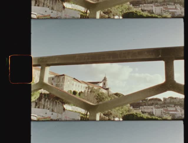 Super 8 film scan shows a view of a historic European city on a hill, framed by a modern railing