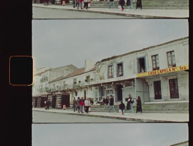 Vintage 8mm film captures people walking along a historic street in Nazaré, Portugal, on a cloudy day