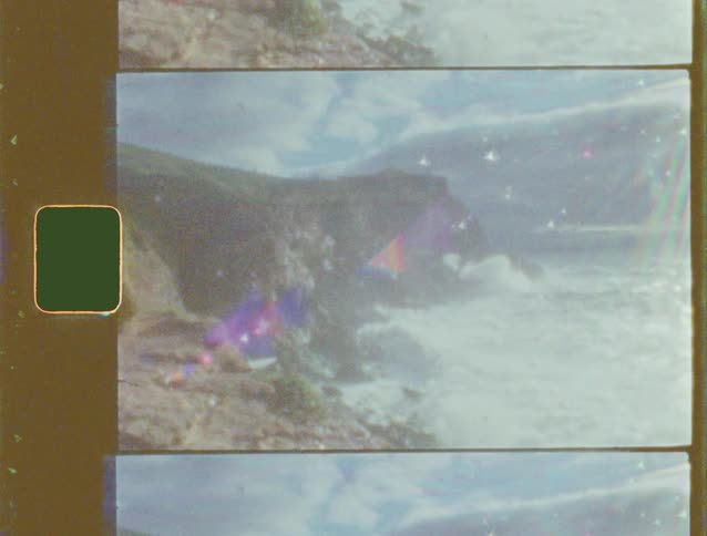 A vintage Super 8 film captures the powerful ocean waves as they crash against the rocky cliffs of the shoreline