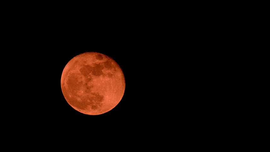 A close-up view of a vibrant red blood moon isolated against the pitch-black night sky