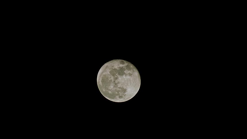 A static, detailed close-up shot of the full moon suspended in the vast darkness of the night sky