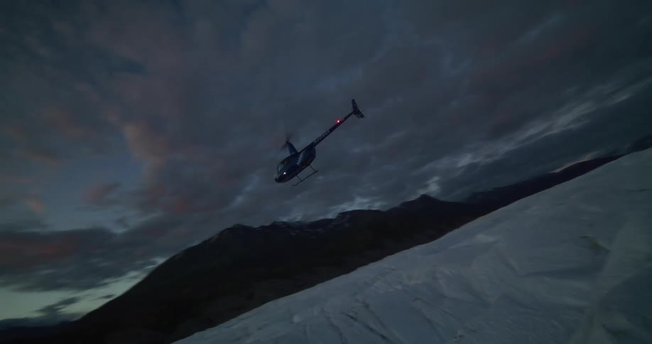 A helicopter flies low over a vast, icy glacier, preparing to land as the sun rises over the mountains