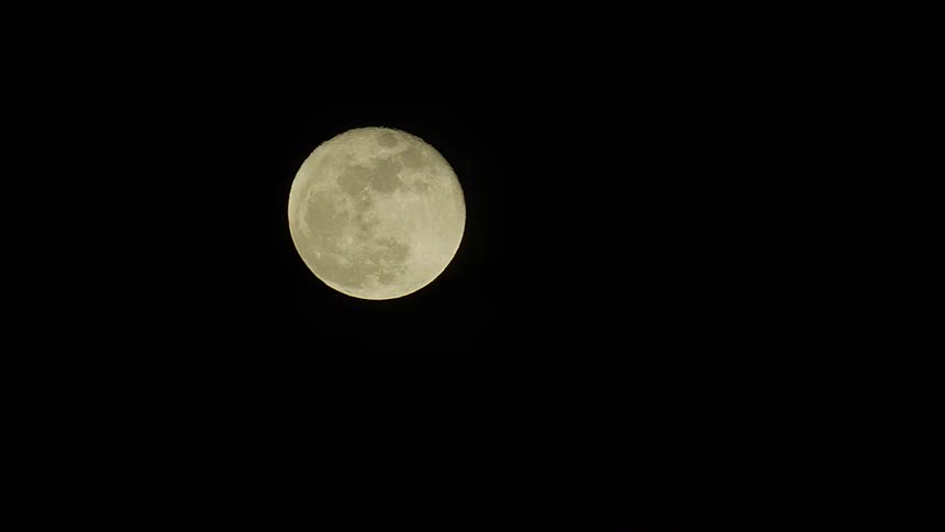 A bright, full moon shines in the pitch-black night sky, its craters and surface details clearly visible