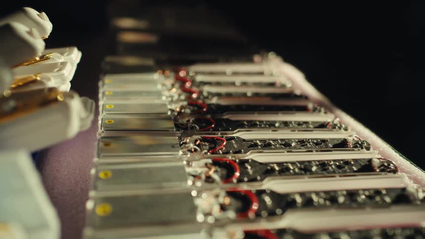 A close-up slow-motion shot reveals a long line of electronic components on a factory assembly line