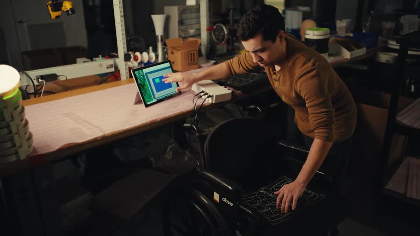 Male engineer tests and calibrates an innovative smart pressure-sensing cushion for a wheelchair in his electronics workshop