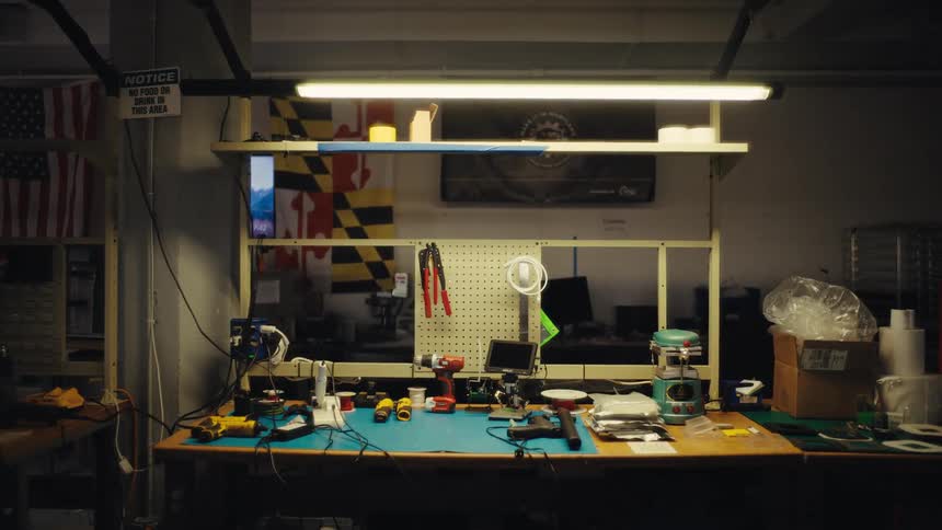 A slow pull back from a cluttered electronics workbench in a dimly lit workshop
