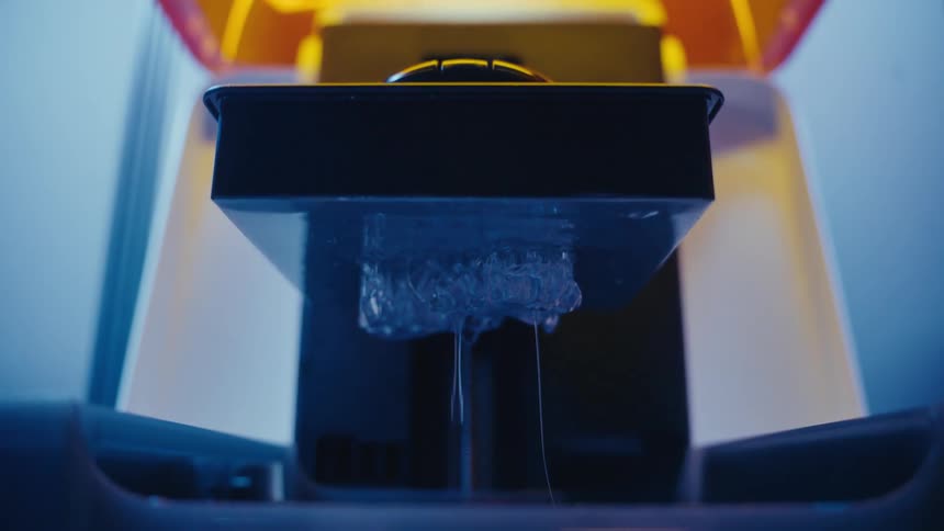 A 3D resin printer lifts a newly created translucent object from the liquid photopolymer bath
