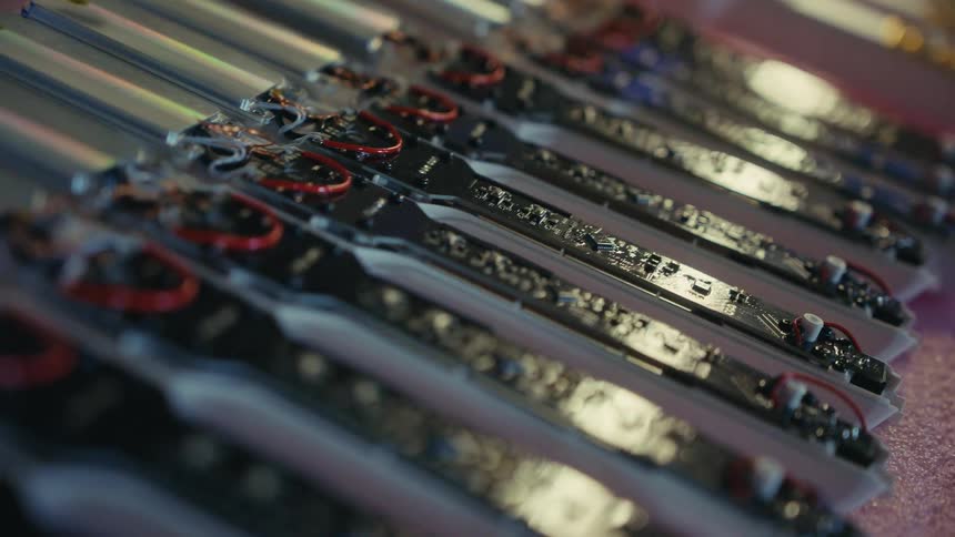 A close-up shot of numerous electronic circuit boards with wiring neatly arranged in a row for assembly