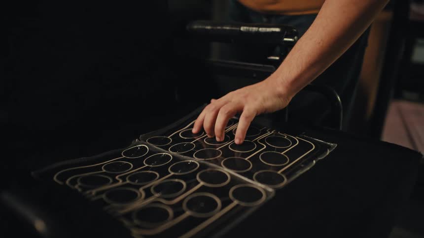 A close-up reveals a hand testing a pressure-sensing mat designed for a wheelchair seat