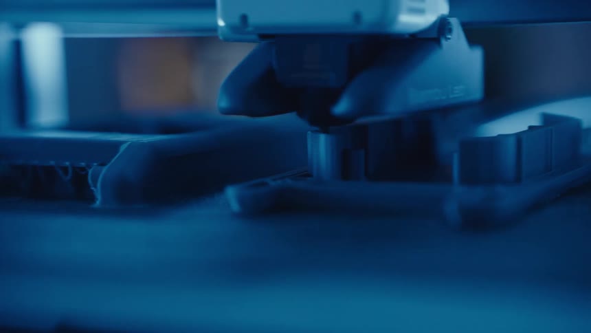 A 3D printer head meticulously builds a plastic component in a futuristic, blue-lit workshop