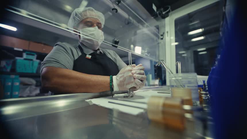 A focused lab technician in full protective gear meticulously works with samples in a sterile laboratory environment