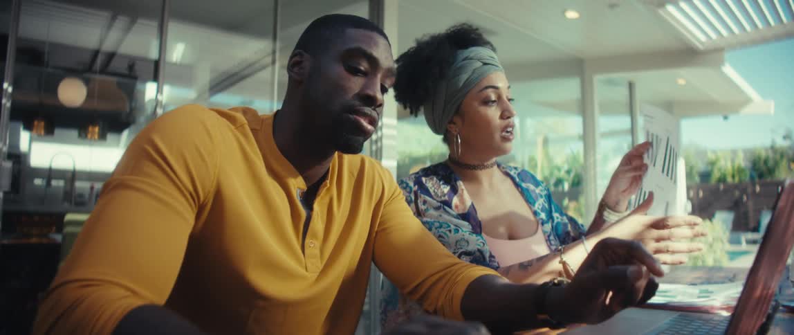 Slow motion push-in shot of a young couple seriously discussing their finances, using a laptop, calculator, and financial charts at a wooden table in their modern home