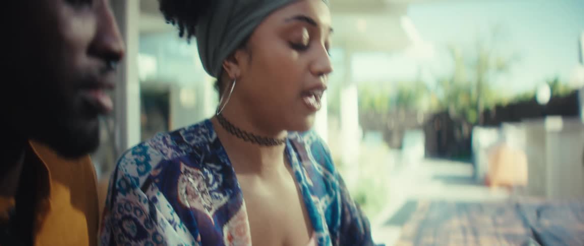 A young Black couple collaborates on a project, with the woman typing on a laptop as they discuss their work together in a bright, modern setting