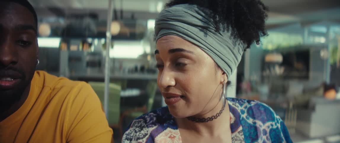 A young African American couple collaborates on their family budget, reviewing papers and using a laptop and calculator at home in slow motion