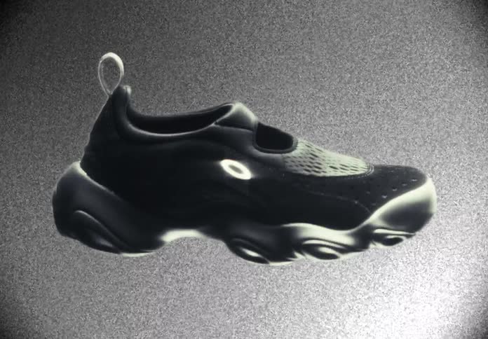 A black sneaker with a chunky sole floats and rotates in a grainy animation, transitioning from monochrome to a warm orange spotlight