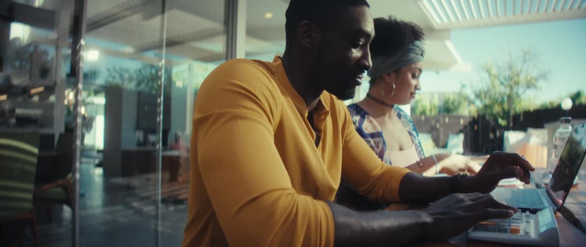 A young couple happily collaborates on their finances with a laptop and documents in their bright, modern home