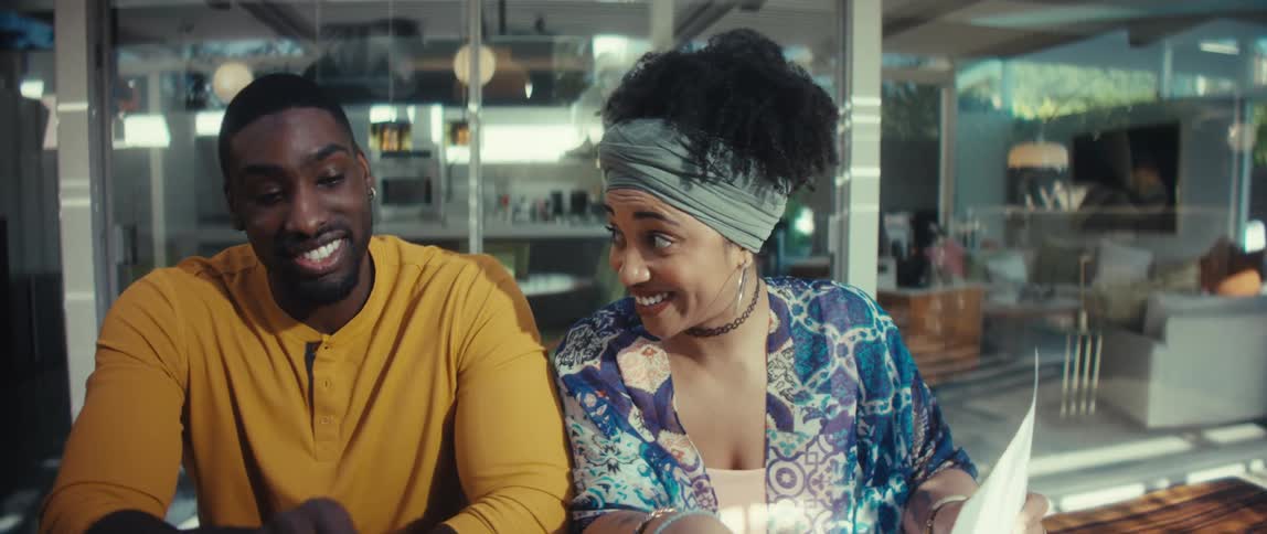 An excited young couple joyfully discusses plans and documents together in their bright, modern home in slow motion