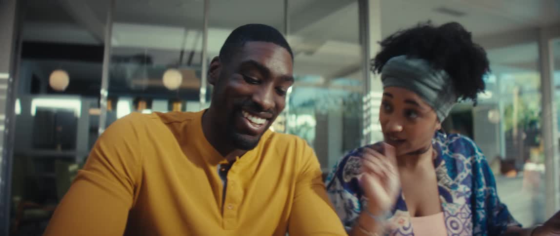A slow-motion close-up reveals a smiling young couple working together on their home finances, using a calculator and a laptop