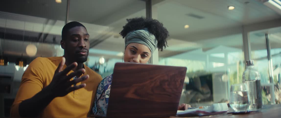 A stylish young African American couple starts a video call on their laptop in a modern home