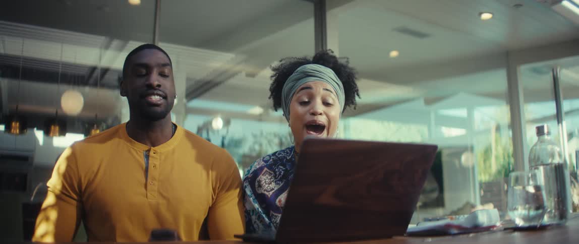 An excited young African American couple celebrates good news they see on their laptop with a slow-motion high-five