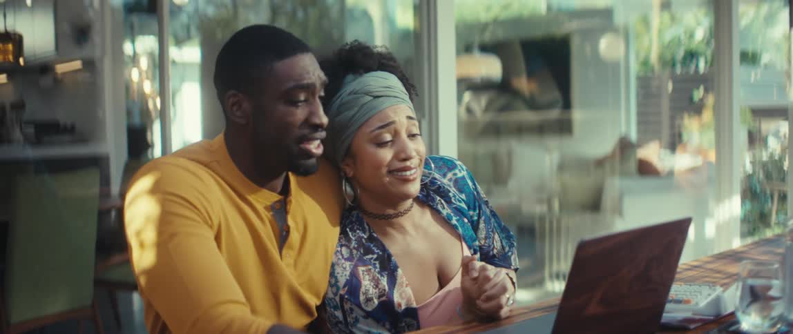 An emotional young couple's expressions shift from surprise to sadness while viewing their laptop screen together at home