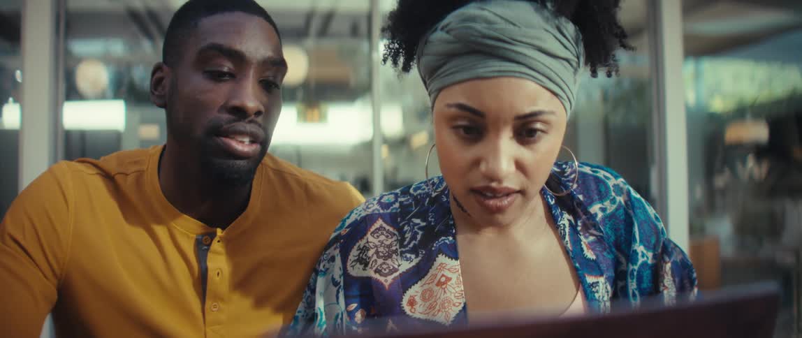A stylish young couple working together on a laptop in a modern space are suddenly shocked by what they see on screen