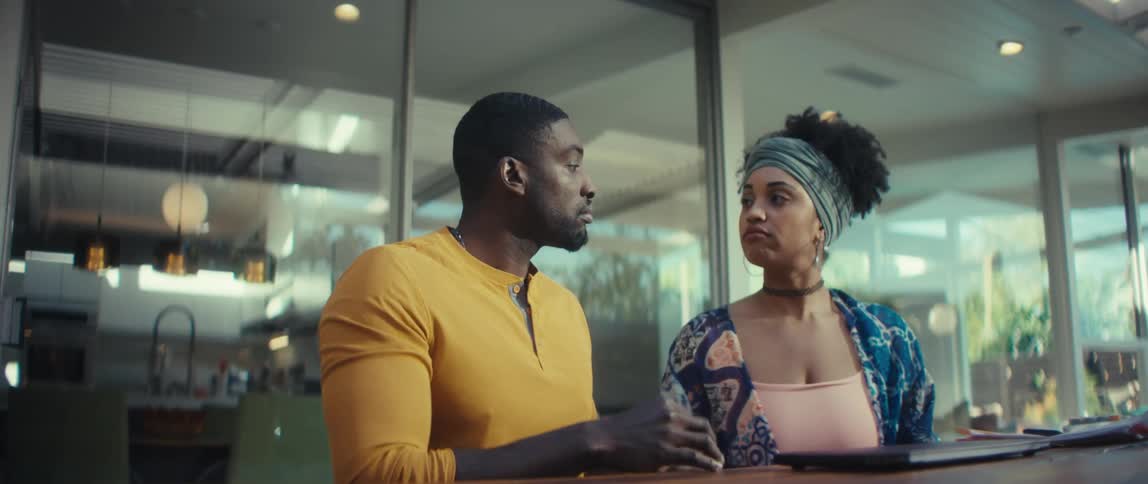 A young couple works together on a laptop, makes an online purchase with a credit card, and has a discussion