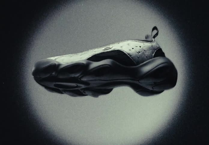 A futuristic black sneaker floats in a grainy black and white spotlight before zooming into extreme close-ups of the sole