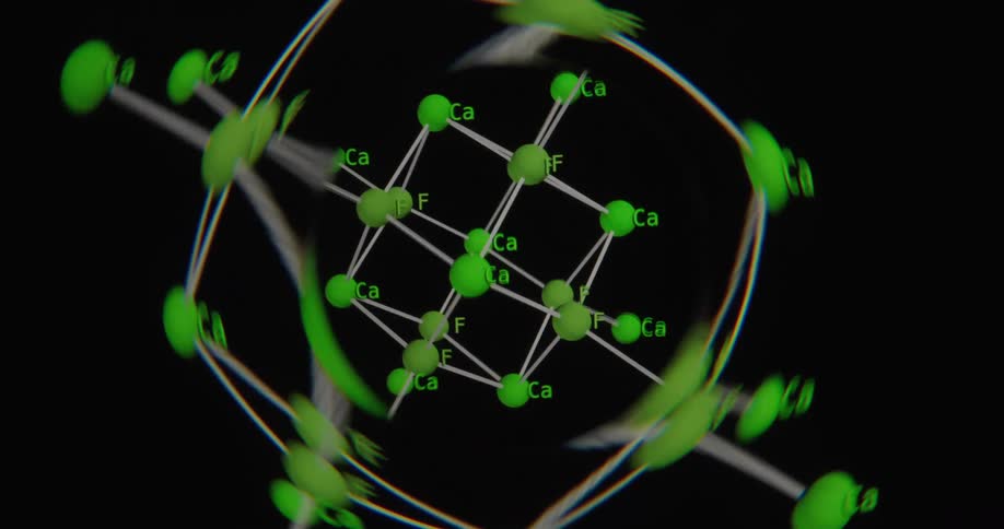 A 3D animated model of a Calcium Fluoride (CaF2) molecule rotates against a black background, demonstrating its crystal lattice structure