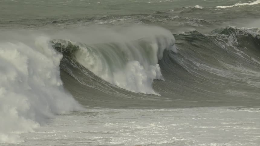 Dramatic slow motion captures a giant, powerful wave curling and breaking in a stormy sea