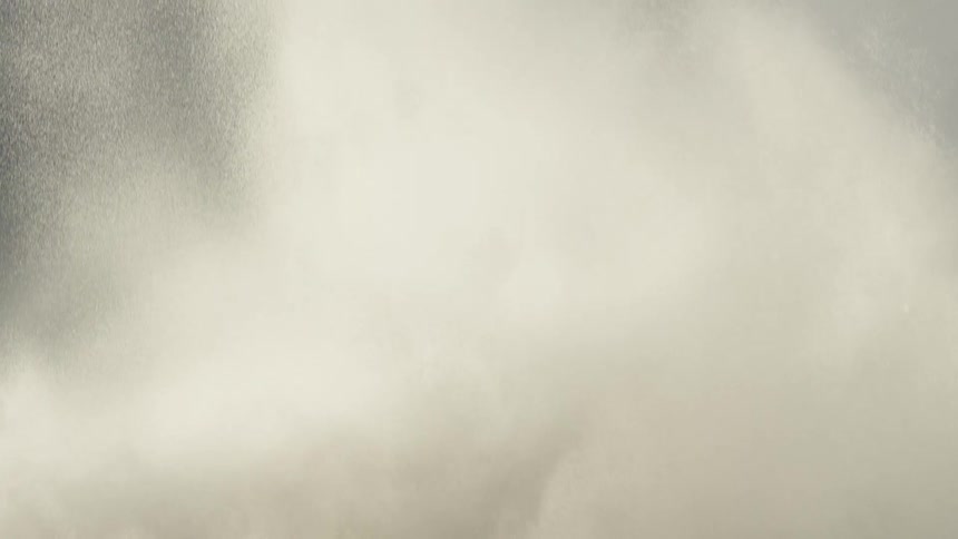 A powerful ocean wave crashes and explodes into a huge cloud of white spray in dramatic slow motion