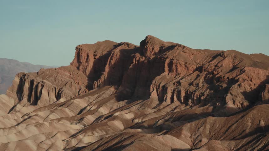 An epic, fast zoom reveals the detailed textures of the layered, red rock formations of a desert mountain range
