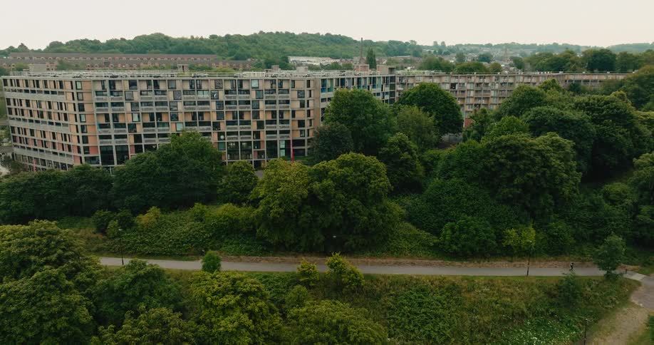 Aerial view slowly pulls back from the iconic brutalist Park Hill flats in Sheffield, surrounded by a lush green park