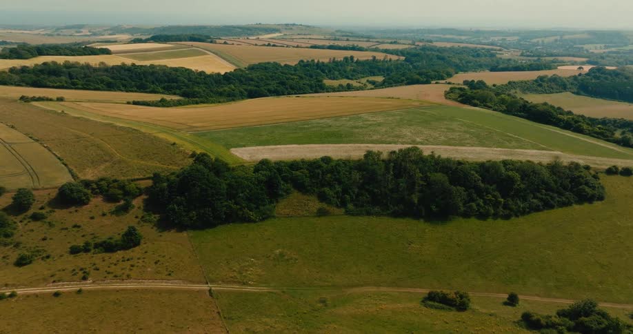 A beautiful aerial view captures the vast patchwork of green pastures and golden fields across the rolling countryside
