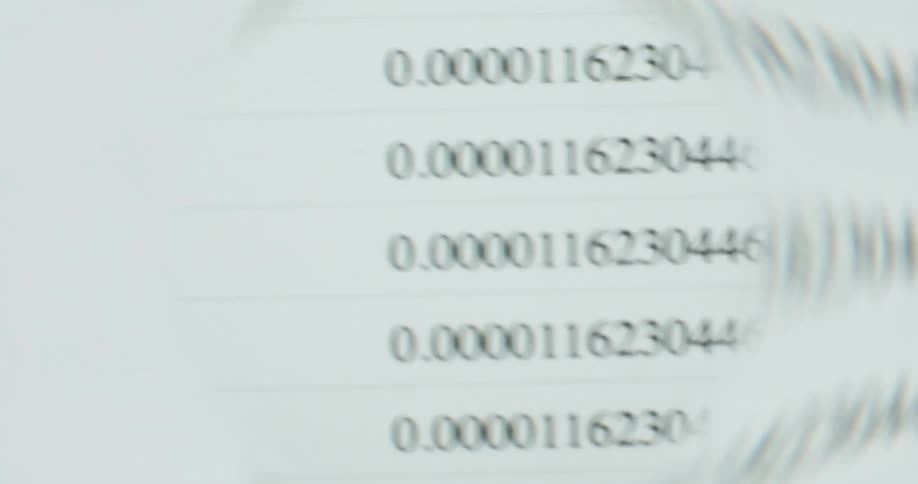 A close-up view through a magnifying glass reveals long decimal numbers on a spreadsheet